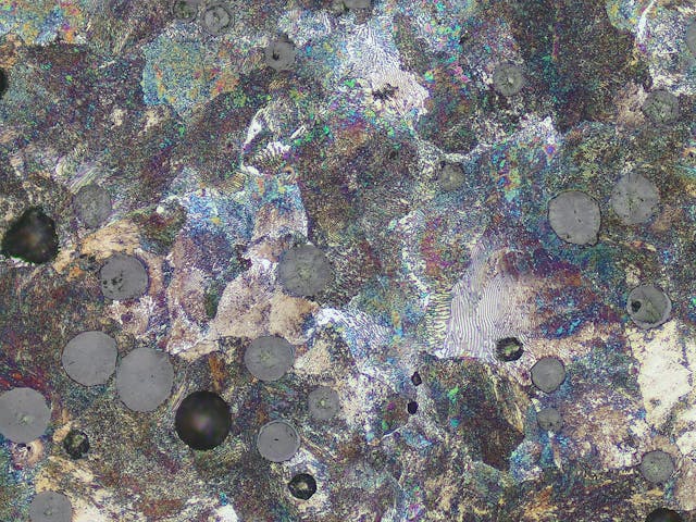 Cast iron with spherulitic graphite. Areas with corrosion and broken out graphite spheres indicate refurbishing of samples.
