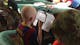 A boy with albinism trying to read a school book with a special visual aid.