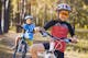 kids on a bicycles in the sunny forest. children cycling outdoors in helmet