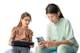 Dve dievčatá s okuliarmi sediace spolu, jedna mladšia a jedna staršia. Mladšie dievča používa tablet a staršie dievča používa smartfón.